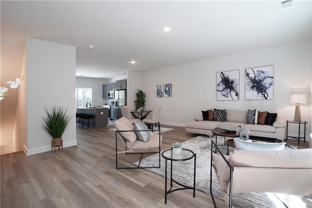 living area featuring recessed lighting, baseboards, visible vents, and light wood-style flooring