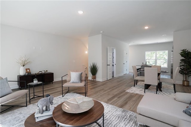 living room featuring baseboards, recessed lighting, and light wood-type flooring