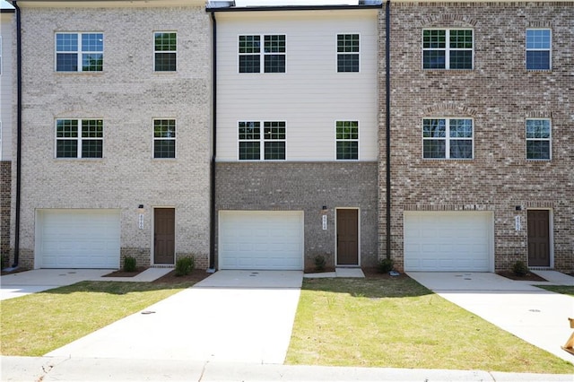 townhome / multi-family property with brick siding, a front lawn, and driveway