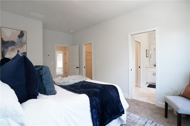 bedroom featuring baseboards, ensuite bath, and a spacious closet