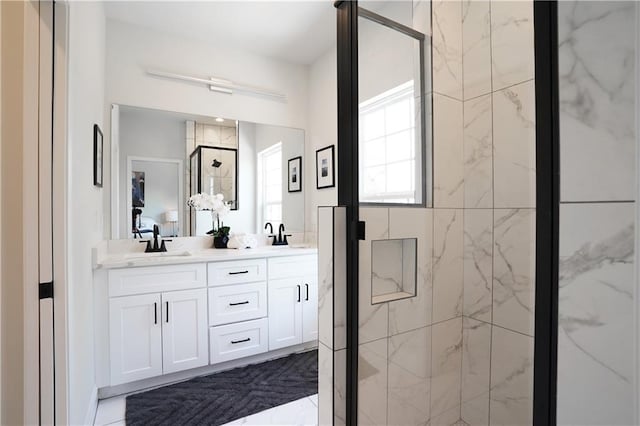 full bathroom with double vanity, a marble finish shower, and a sink