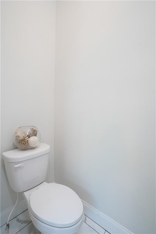 bathroom featuring baseboards, marble finish floor, and toilet