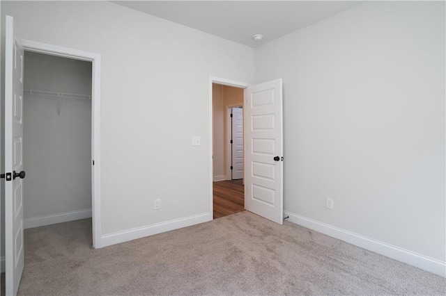 unfurnished bedroom featuring baseboards, carpet, and a closet