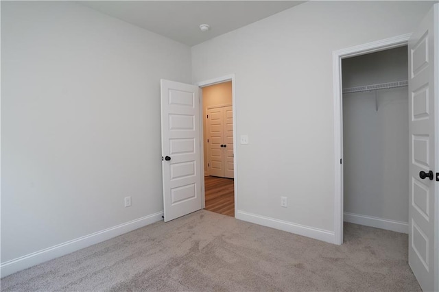 unfurnished bedroom with carpet floors, baseboards, and a closet