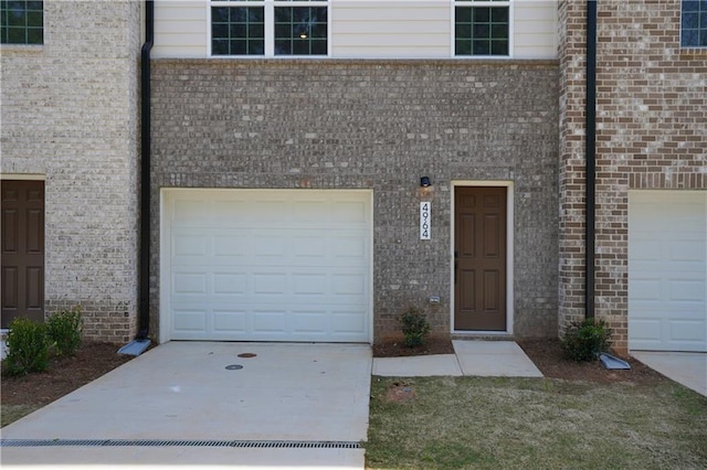 view of front of home featuring an attached garage, driveway, and brick siding