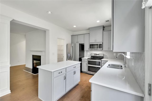 5312 Brooklands Dr, Lithonia, GA 30058 - kitchen with appliances with stainless steel finishes, a center island, backsplash, light countertops, and gray cabinetry