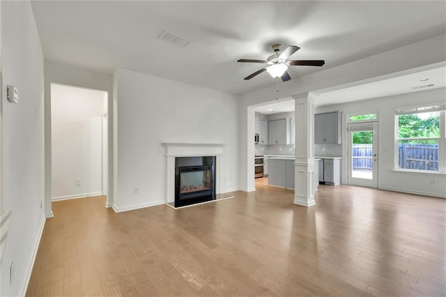 5312 Brooklands Dr, Lithonia, GA 30058 - unfurnished living room featuring ceiling fan, light wood finished floors, a glass covered fireplace, and decorative columns