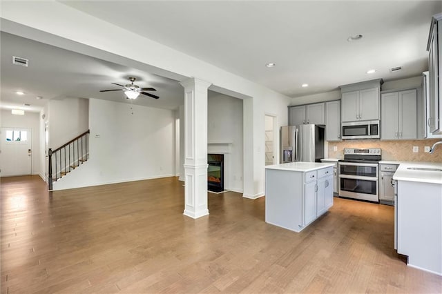 5312 Brooklands Dr, Lithonia, GA 30058 - kitchen with appliances with stainless steel finishes, open floor plan, a kitchen island, light countertops, and a multi sided fireplace
