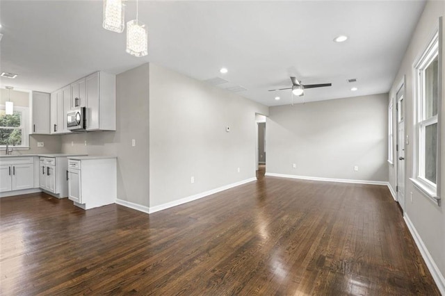 unfurnished living room featuring ceiling fan and dark hardwood / wood-style flooring