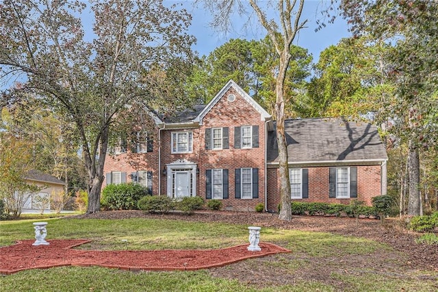 colonial inspired home with brick siding and a front yard