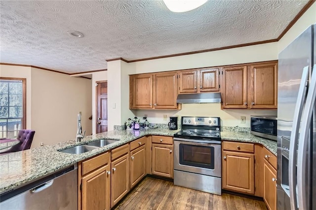 kitchen with light stone counters, dark wood finished floors, a sink, stainless steel appliances, and under cabinet range hood