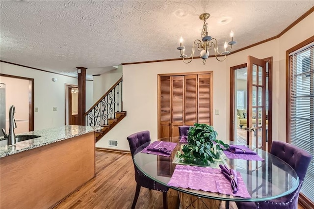 dining space with visible vents, crown molding, a chandelier, stairs, and light wood-style floors