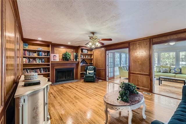 living room featuring wooden walls, a fireplace, light wood-type flooring, and a wealth of natural light