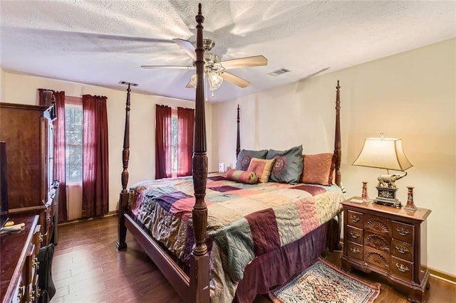 bedroom with ceiling fan, wood finished floors, visible vents, and a textured ceiling