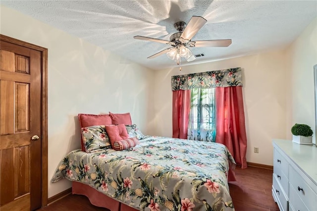 bedroom featuring visible vents, dark wood-type flooring, a textured ceiling, and a ceiling fan