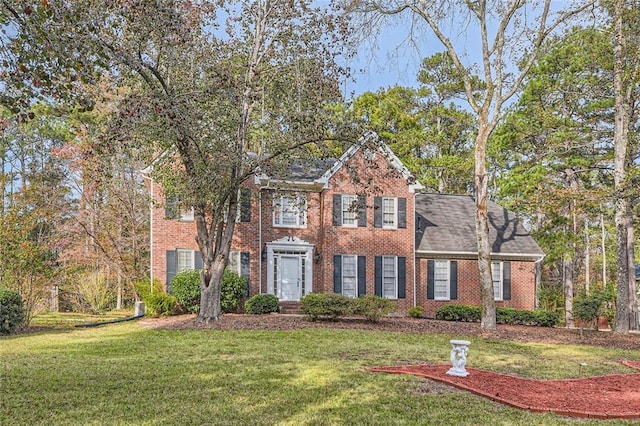 colonial-style house featuring brick siding and a front yard