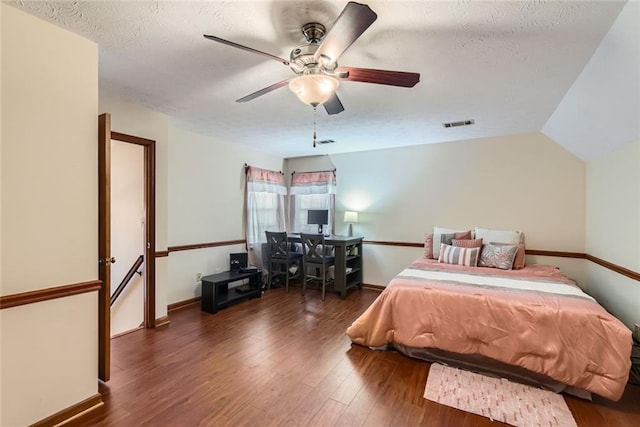 bedroom featuring visible vents, a textured ceiling, wood finished floors, baseboards, and lofted ceiling