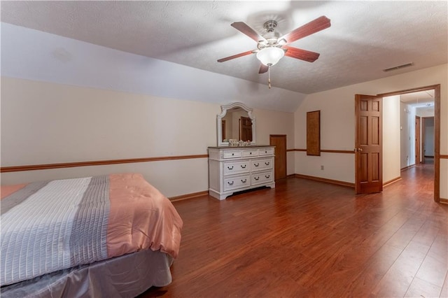 bedroom with lofted ceiling, wood finished floors, visible vents, and a textured ceiling