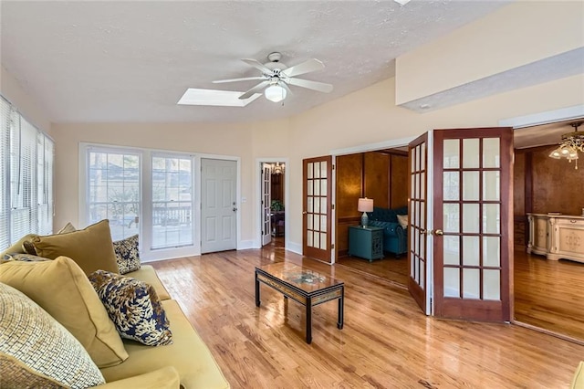 living area with french doors, light wood finished floors, ceiling fan, and vaulted ceiling