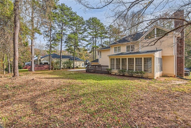 exterior space with a chimney, a yard, and a sunroom