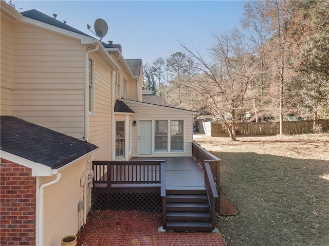 view of side of property with a deck, fence, and brick siding