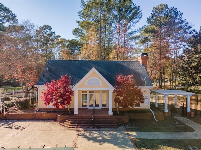 view of front of house with fence, roof with shingles, and a chimney