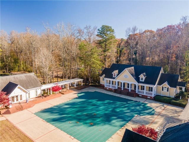 view of swimming pool with a wooded view