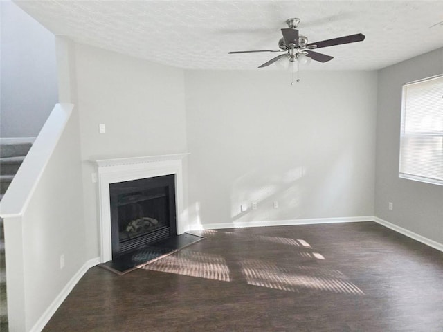 unfurnished living room with dark wood-type flooring, ceiling fan, and a textured ceiling