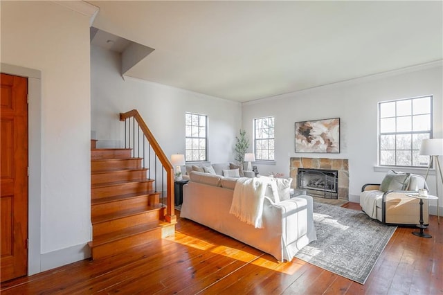 living room with crown molding, hardwood / wood-style flooring, and a stone fireplace