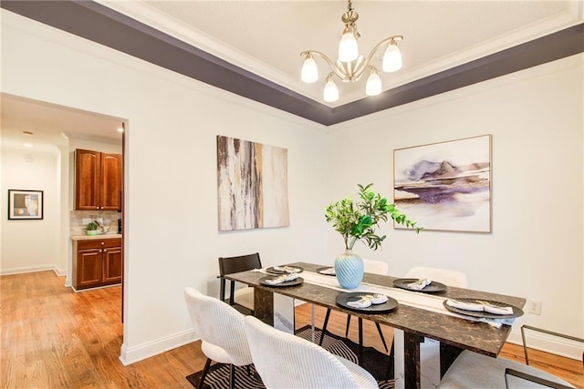 dining space with crown molding, light hardwood / wood-style flooring, and a chandelier