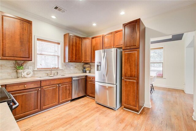 kitchen featuring sink, light hardwood / wood-style flooring, a healthy amount of sunlight, and appliances with stainless steel finishes