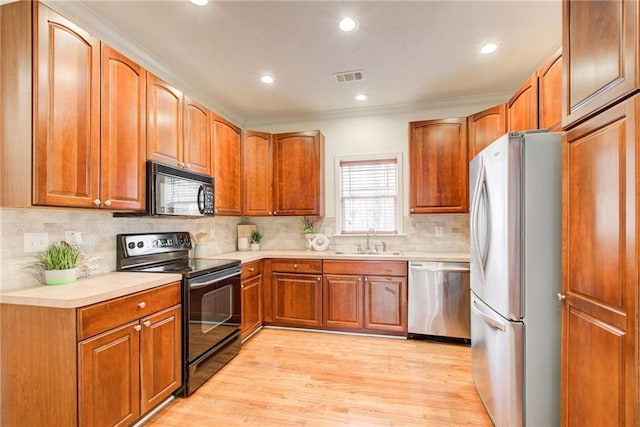 kitchen featuring decorative backsplash, sink, black appliances, and light hardwood / wood-style floors