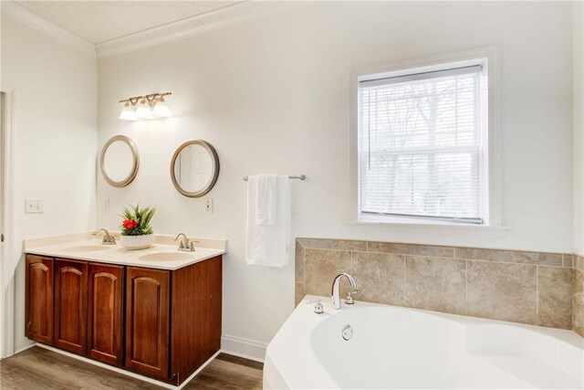 bathroom with plenty of natural light, ornamental molding, a tub to relax in, and vanity