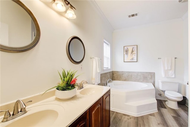 bathroom featuring hardwood / wood-style floors, vanity, a bathing tub, toilet, and ornamental molding