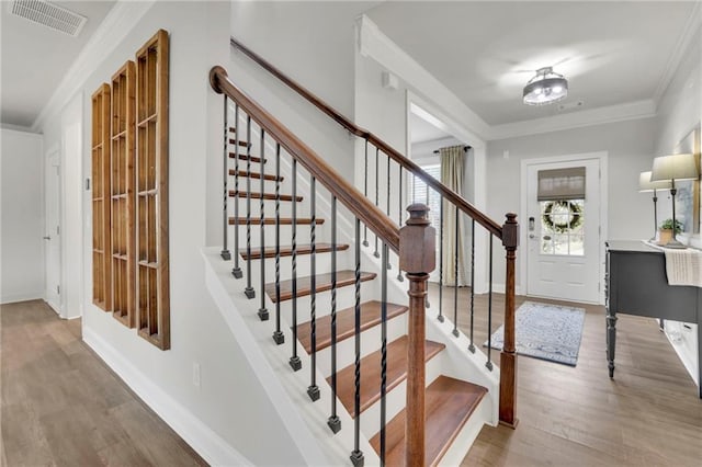 entryway with ornamental molding, visible vents, stairway, wood finished floors, and baseboards