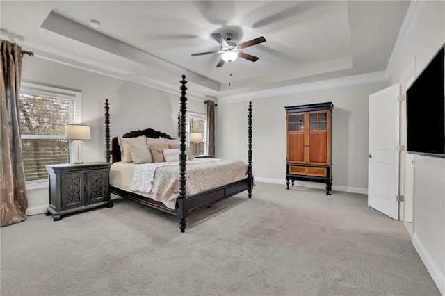 bedroom featuring baseboards, ornamental molding, a raised ceiling, ceiling fan, and carpet