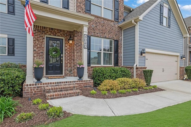 doorway to property featuring brick siding, an attached garage, and concrete driveway