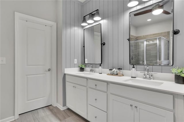 full bathroom with a sink, double vanity, a stall shower, and a ceiling fan
