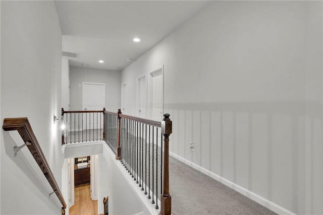 hallway featuring visible vents, baseboards, an upstairs landing, and recessed lighting