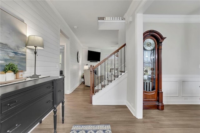 foyer featuring crown molding, light wood-style flooring, and stairway