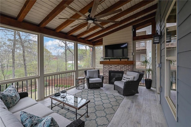 sunroom / solarium featuring beamed ceiling, ceiling fan, and an outdoor living space with a fireplace