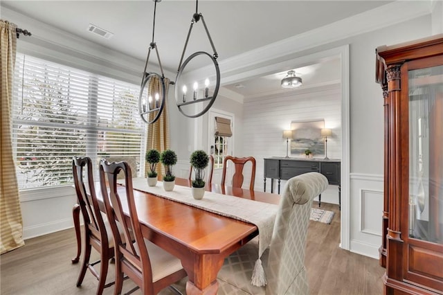 dining space with crown molding, visible vents, an inviting chandelier, and wood finished floors