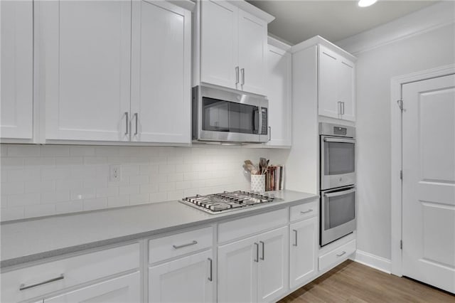 kitchen featuring appliances with stainless steel finishes, decorative backsplash, light countertops, and white cabinetry