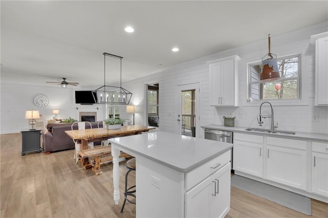 kitchen with light countertops, a fireplace, a sink, and light wood-style flooring
