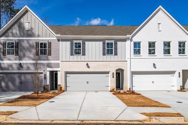 view of front facade with driveway, an attached garage, brick siding, and board and batten siding