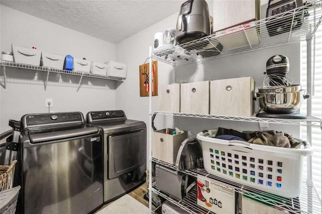 laundry area with a textured ceiling, laundry area, separate washer and dryer, and wood finished floors