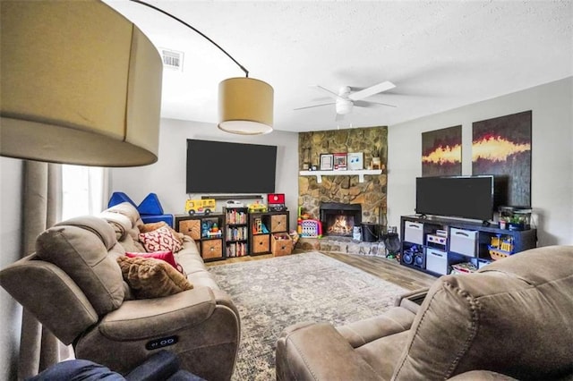 living area with visible vents, ceiling fan, wood finished floors, a textured ceiling, and a fireplace