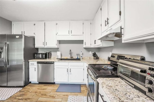 kitchen with appliances with stainless steel finishes, light wood-style floors, white cabinetry, a sink, and under cabinet range hood