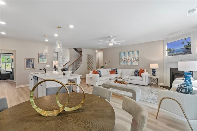 living room featuring sink, ceiling fan, and light wood-type flooring