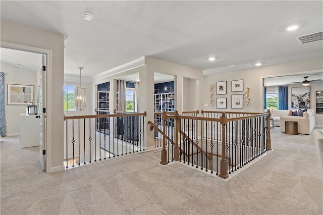 hallway featuring an inviting chandelier, light carpet, and a wealth of natural light